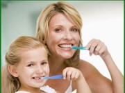 Picture of a mother and daughter brushing their teeth and practicing preventive dentistry.