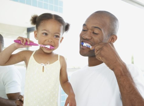 Picture of a father a daughter brushing their teeth.